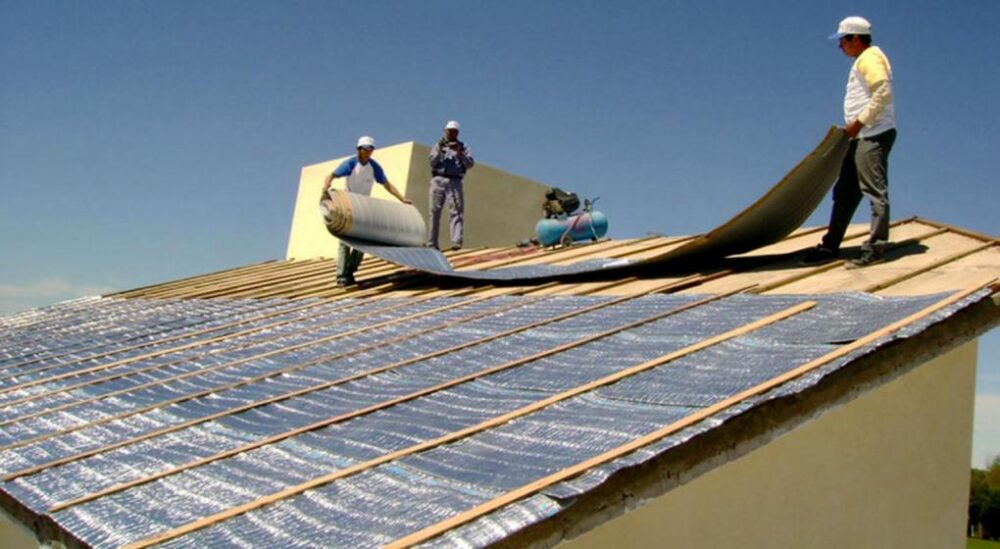 Trabajadores colocando aislantes termicos sobre una cubierta para optimizar el aislamiento y el confort interior de la construccion